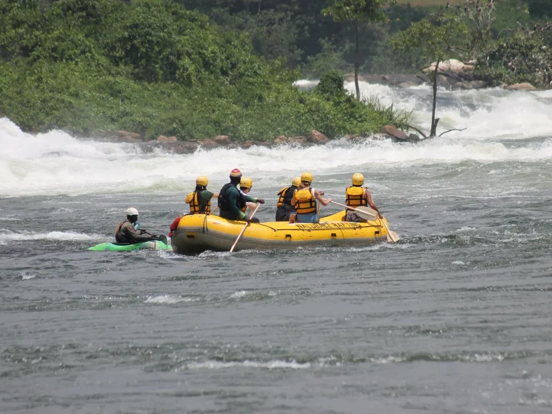 Rafters paddling below big rapids on the Nile near Jinja with a safety kayaker
